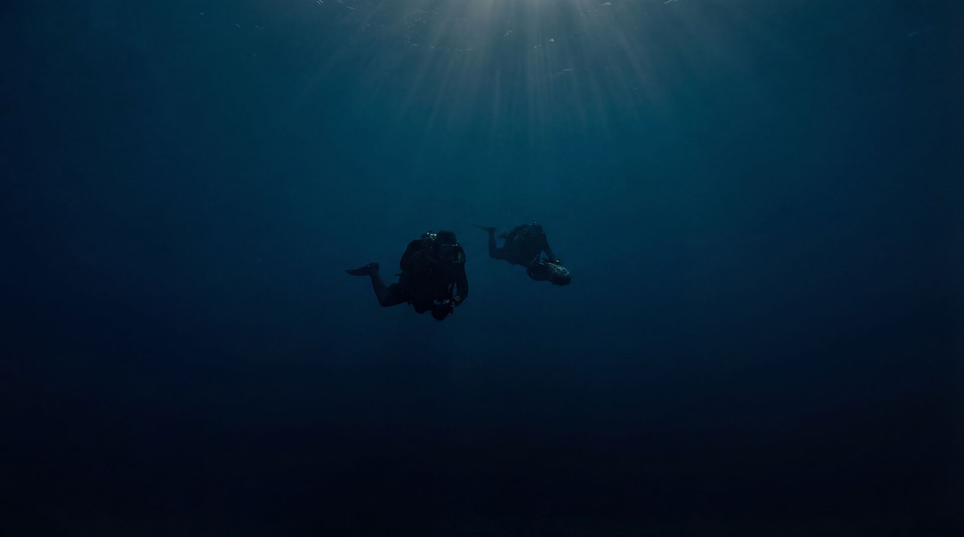 Silhouettes de plongeurs dans un bleu abyssal : mystère et exploration